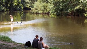 Two people sitting next to the river Saale in Jena